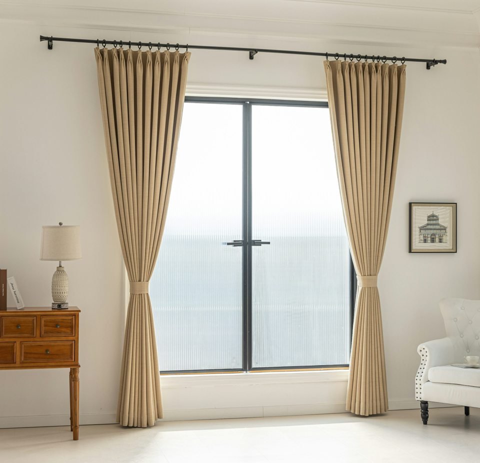 Tied-back pleated beige drapes framing a broad window.