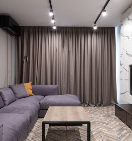 Gray L-shaped sofa beside curtains and a TV in a living room.