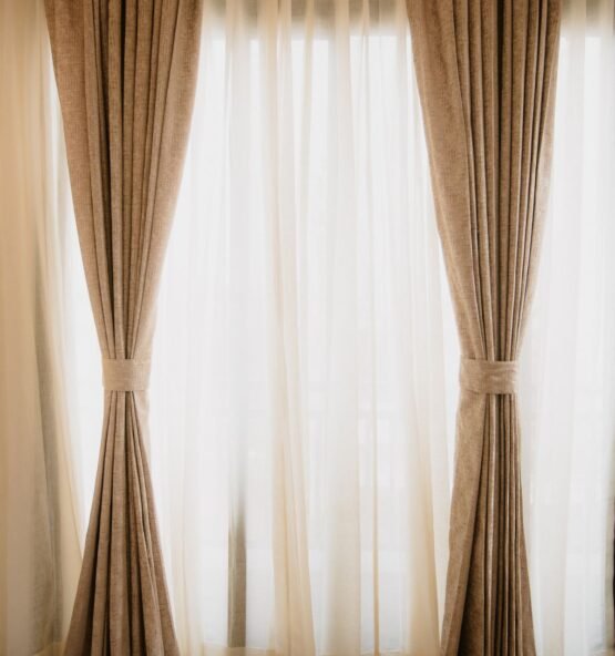 Beige drapes tied back beside sheer white curtains.
