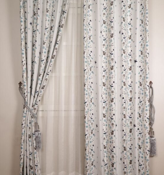Printed white drapes layered over sheer curtains at a window.