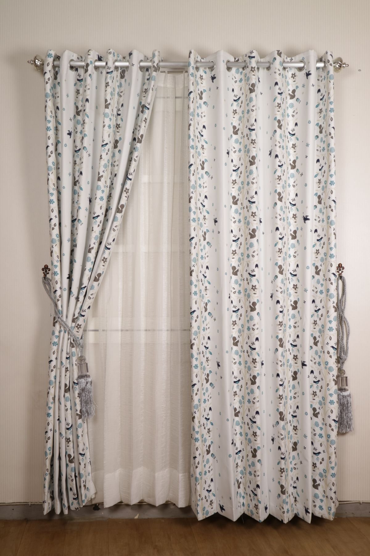 Printed white drapes layered over sheer curtains at a window.
