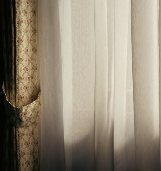 Textured patterned drapes beside soft white sheer curtains.