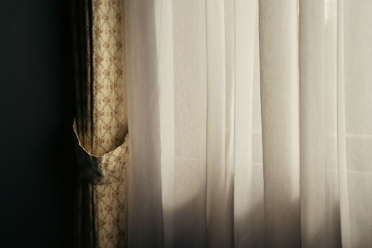 Textured patterned drapes beside soft white sheer curtains.
