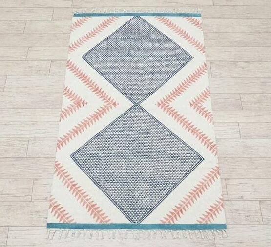 Light rug with blue diamond motifs and coral accents on a wooden floor.