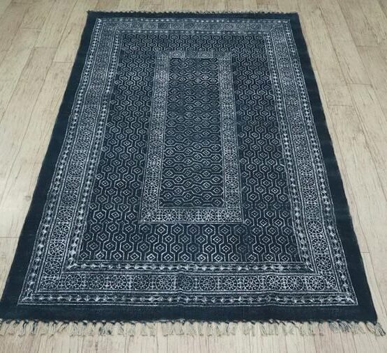 Dark navy patterned rug with a pale border and fringed edge.