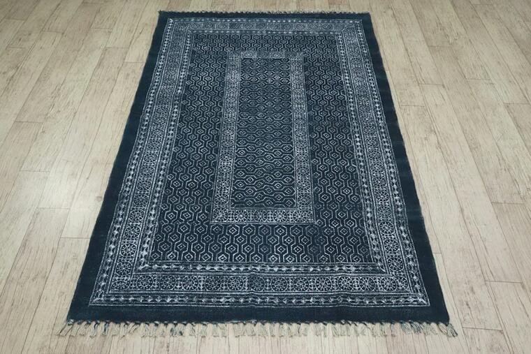 Dark navy patterned rug with a pale border and fringed edge.