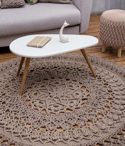Round crochet-style rug beneath a coffee table in a neutral living room.