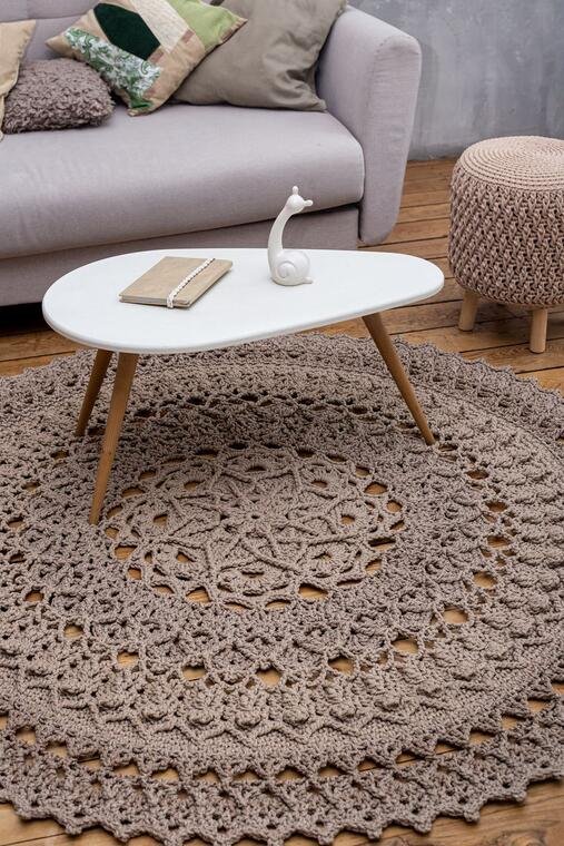 Round crochet-style rug beneath a coffee table in a neutral living room.